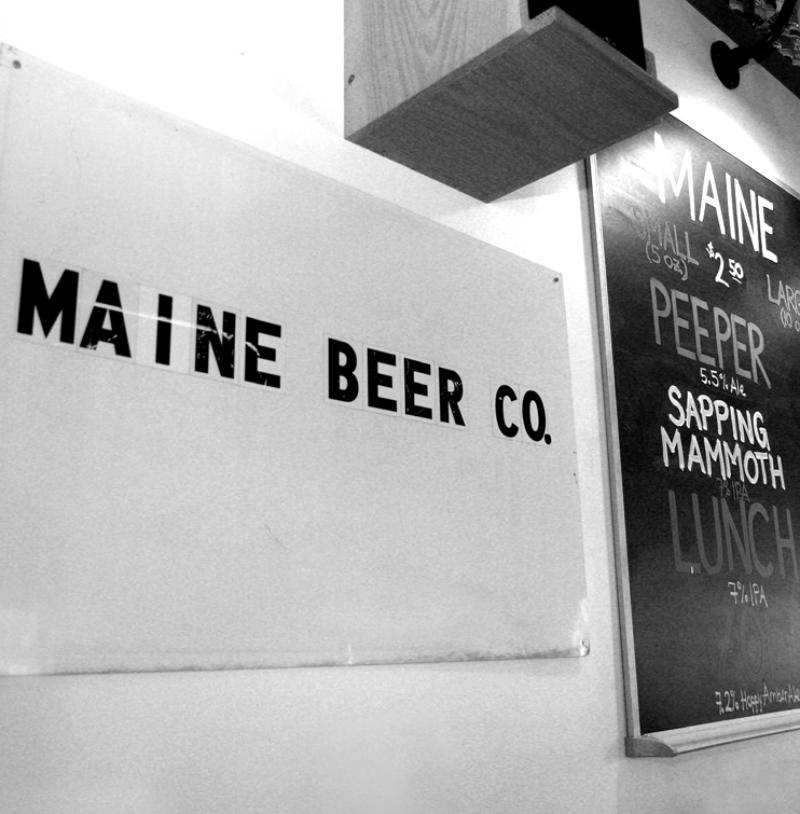 A black and white photo of the original Maine Beer Company sign, a simple white sign with black sticker letters that says "Maine Beer Co."