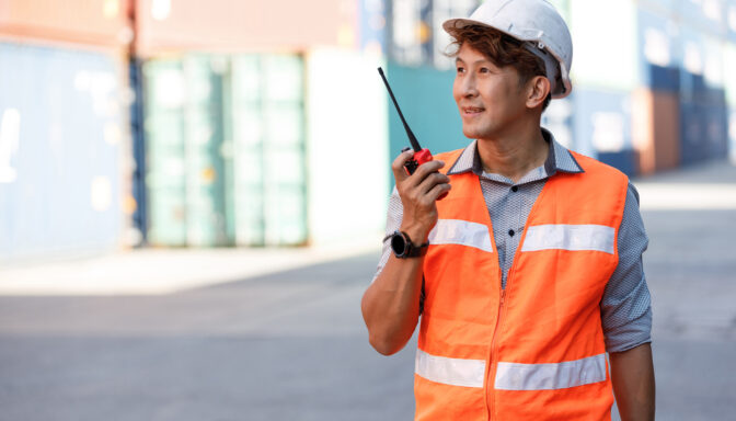 A manufacturing employee communicating with other coworkers via a walkie talkie.