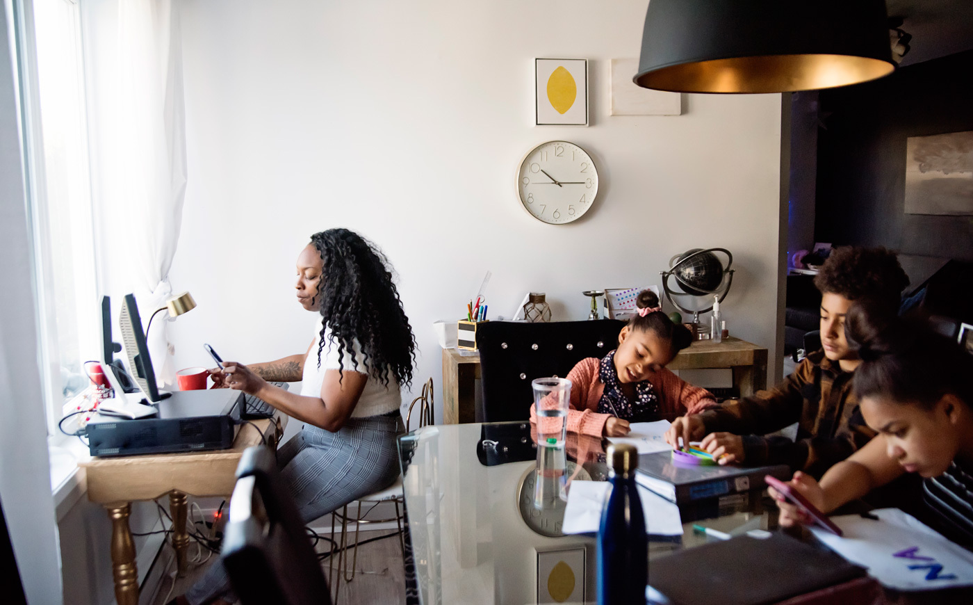 Mother sitting at a desk looking at her phone while kids color